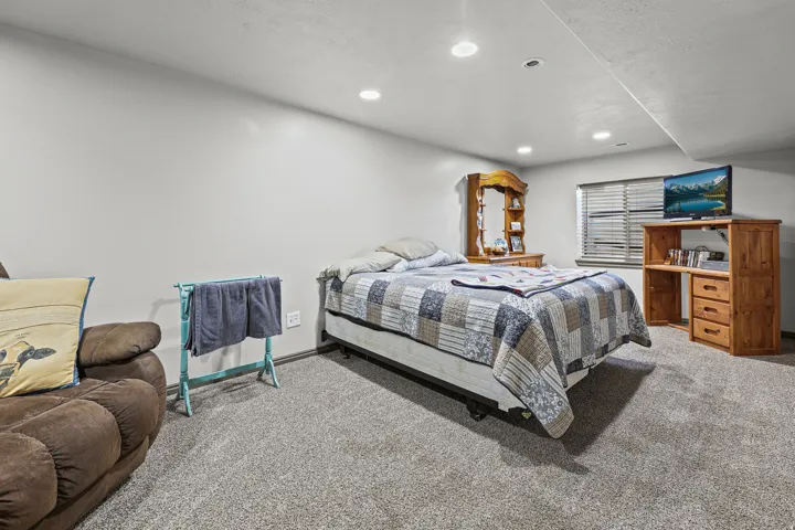 Recessed lighting illuminates the space, featuring gray carpeting and a window with blinds