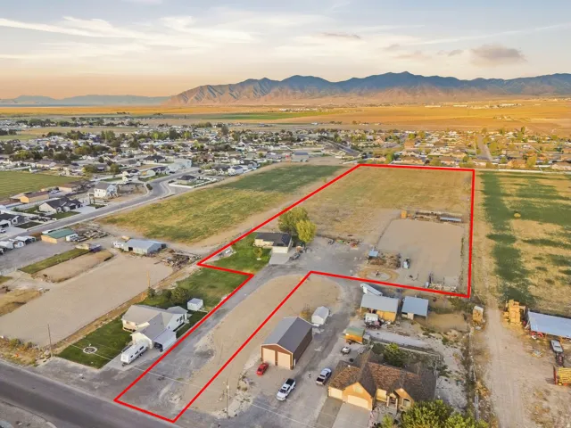 Expansive open land with defined property boundaries, a single-story residence, and an auxiliary building
