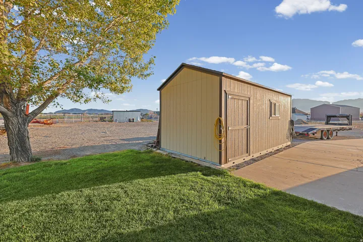 Detached storage shed with a window, concrete pad, and adjacent grass area