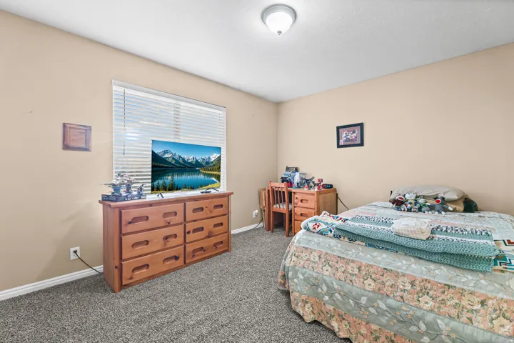 Textured carpet flooring, window with horizontal blinds, flush mount ceiling light, and neutral wall tones