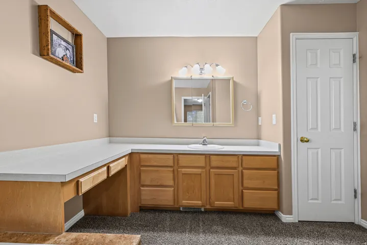 L-shaped vanity with integrated sink, wood-finish cabinetry, and white countertops