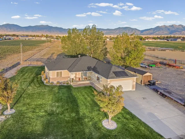 Expansive green lawn, concrete driveway, attached two-car garage, multiple outbuildings, and solar panels