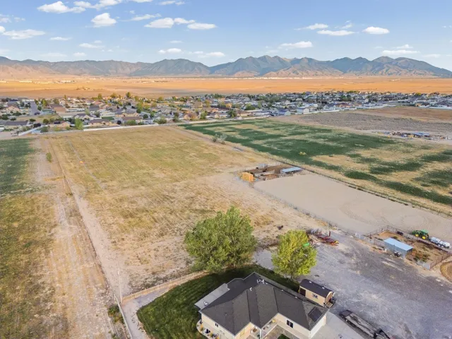 Expansive property featuring a gravel driveway, mature trees, manicured lawn, and a distant mountain range