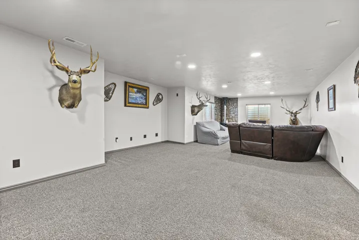Recessed lighting illuminates the open-concept space, featuring light gray carpeting and white painted walls