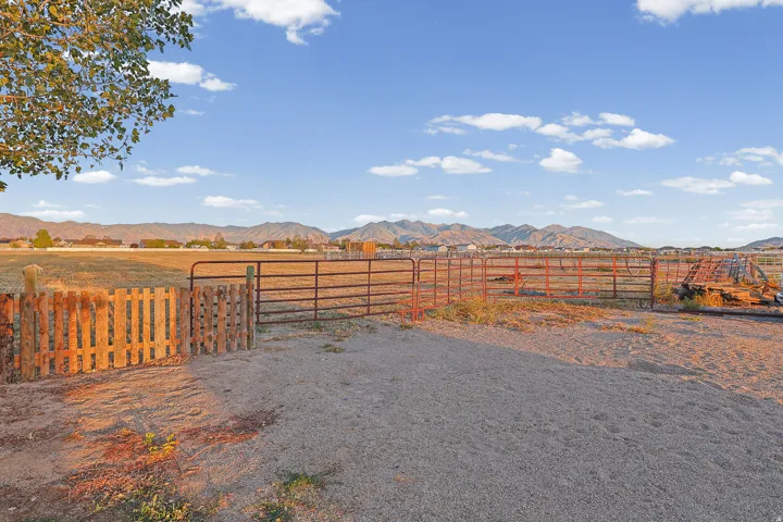 Fenced outdoor area with a wooden gate, metal fencing, and a gravel surface