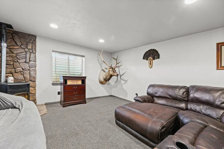 Stone-clad fireplace with wood-burning stove, recessed lighting, and carpeted flooring