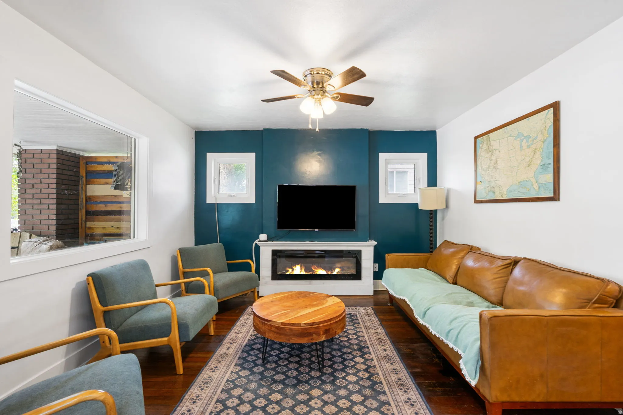 Wood-finish flooring, ceiling fan, built-in fireplace, and a large interior window