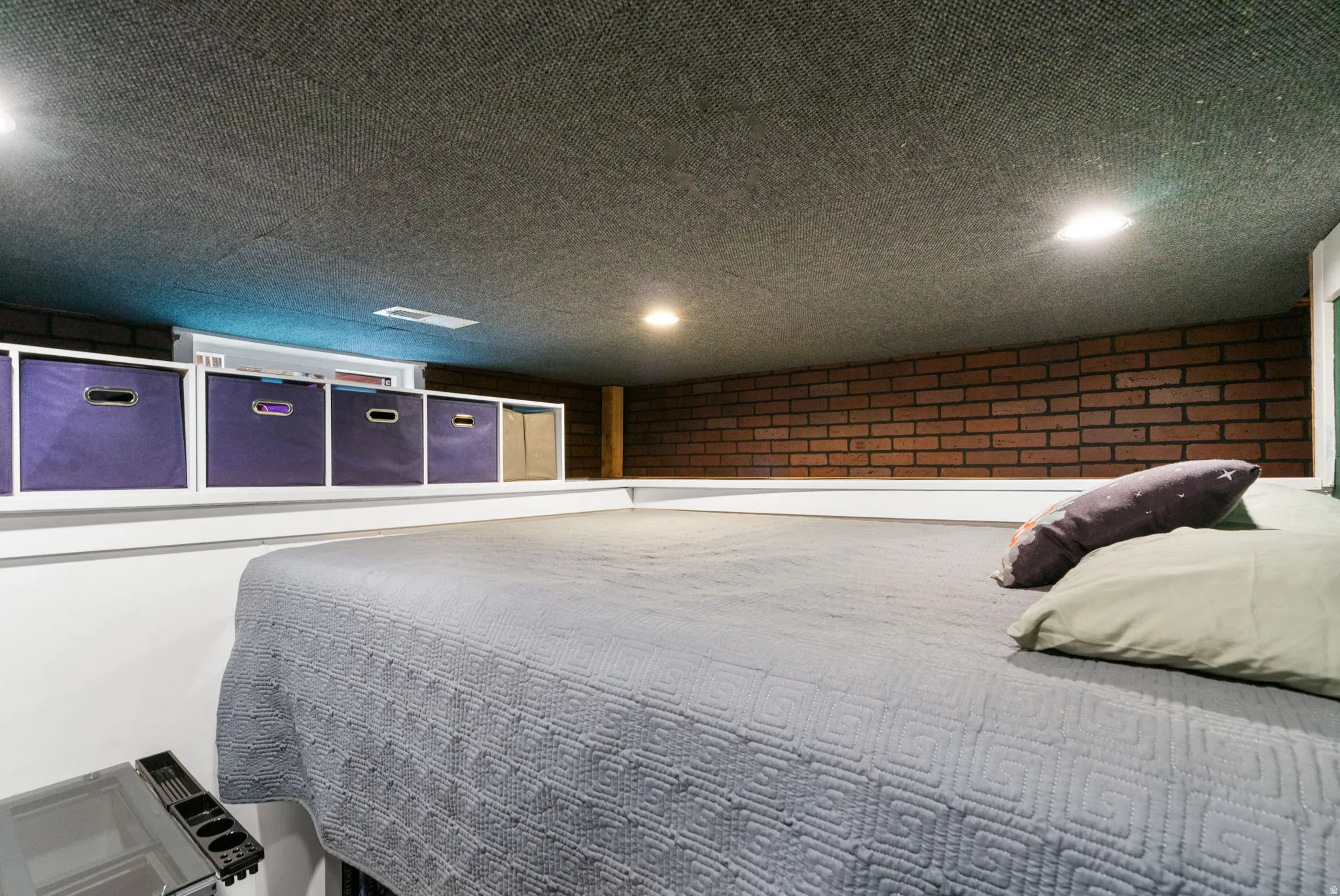 Exposed brick wall detail, recessed lighting, and built-in shelving