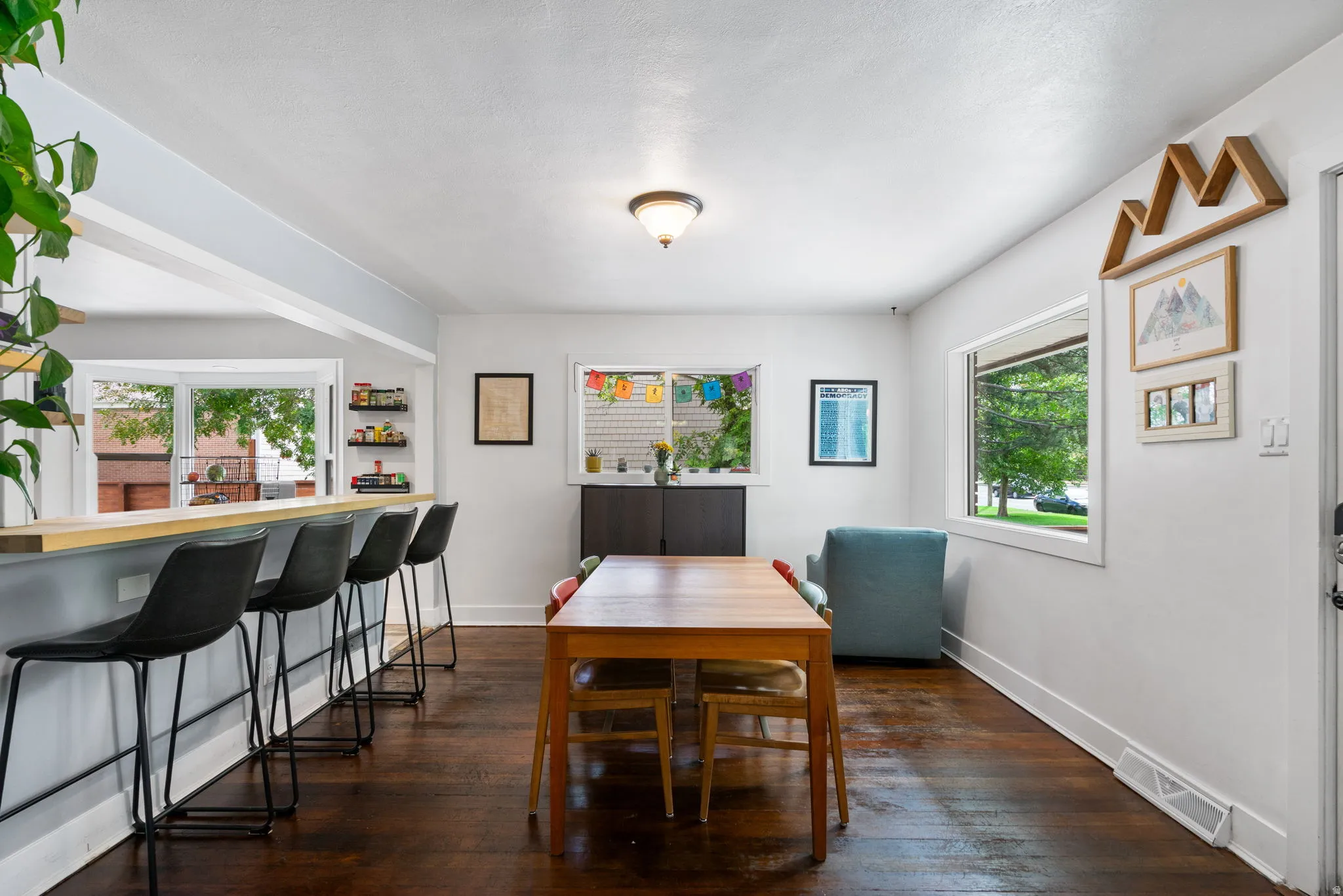 Hardwood flooring throughout, recessed lighting fixture, multiple windows providing natural illumination, and a built-in breakfast bar with a wood-finish countertop