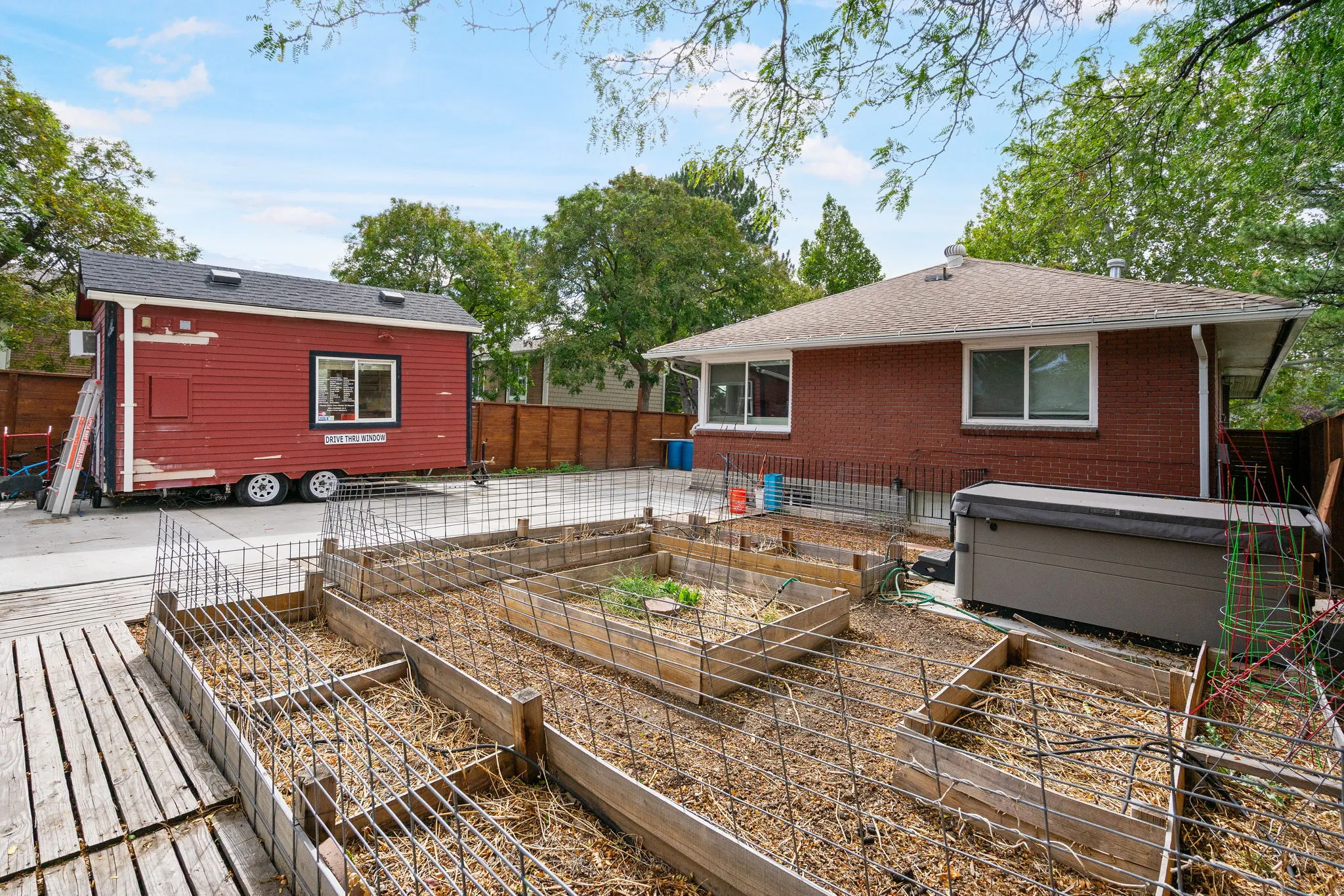Backyard featuring raised garden beds, a hot tub, and a red auxiliary structure with a dark roof