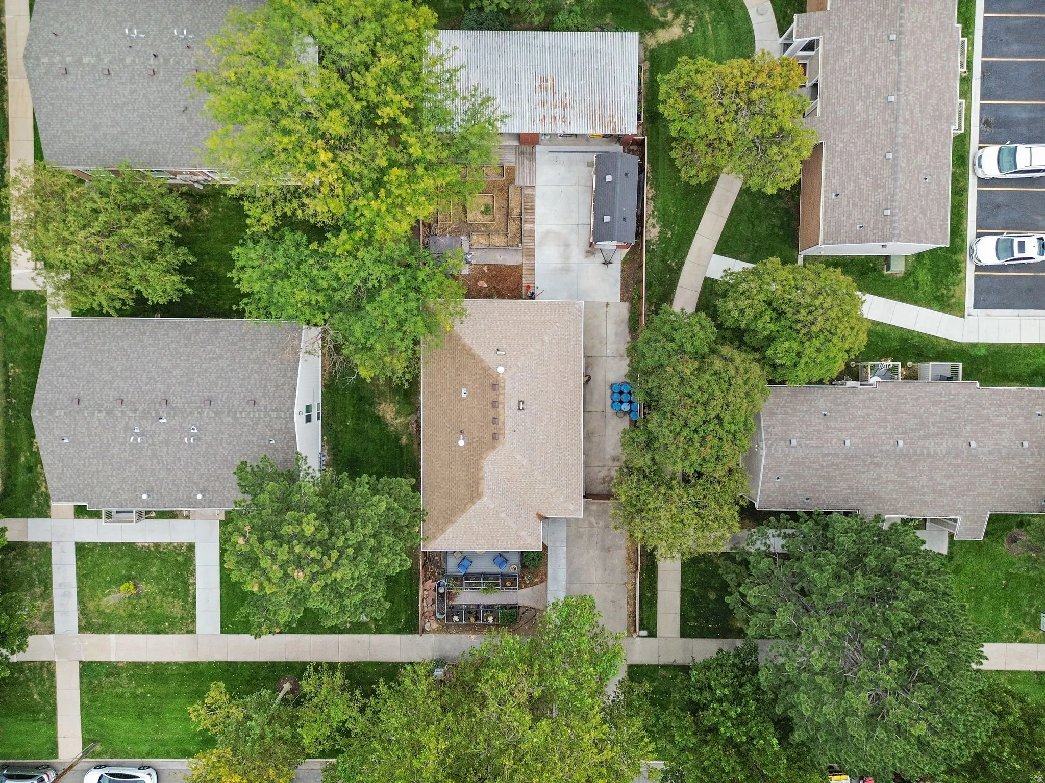 Aerial property overview featuring a shingle roof, concrete drive, and mature trees