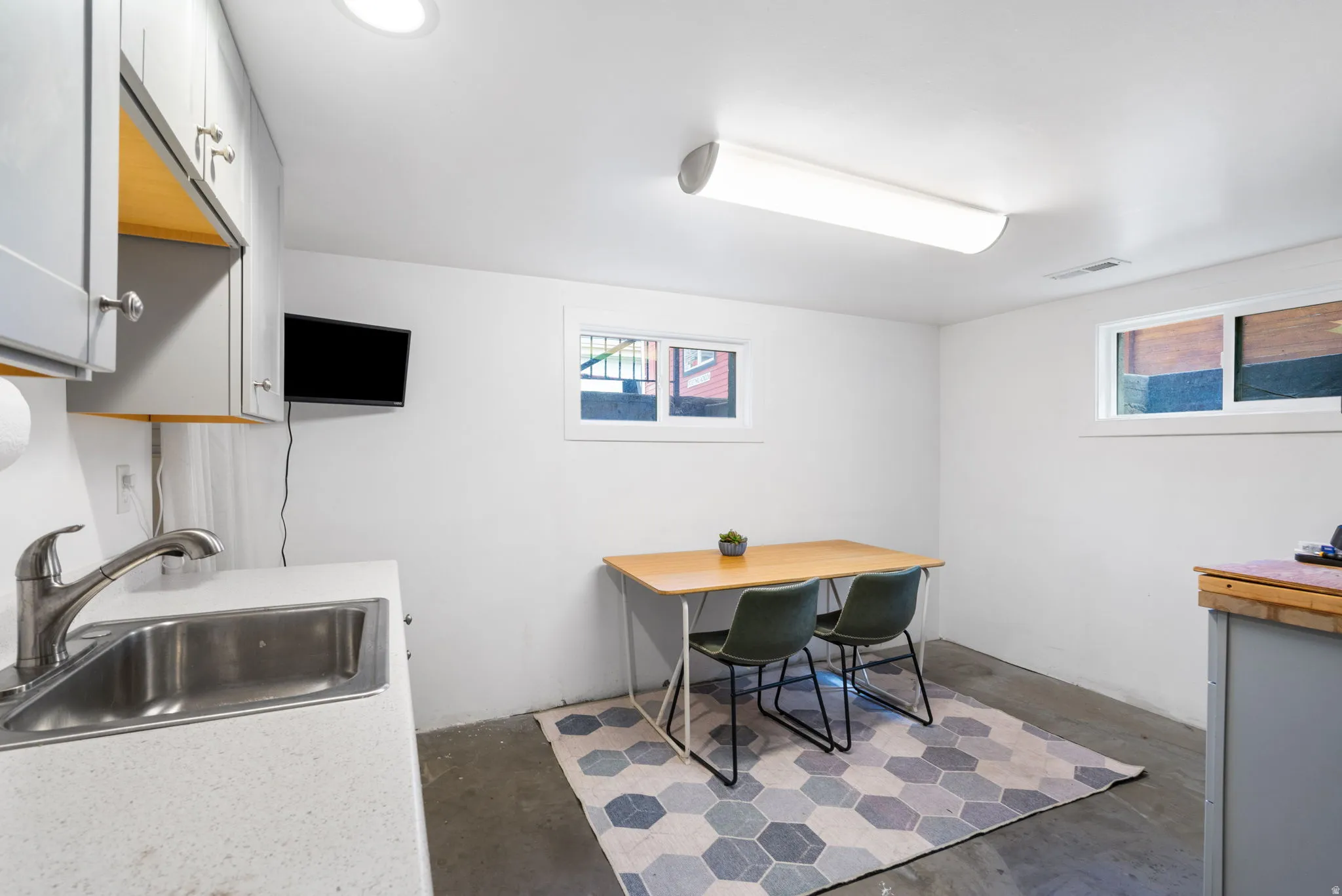 Full-size stainless steel sink, solid surface countertop, built-in cabinetry, and recessed lighting