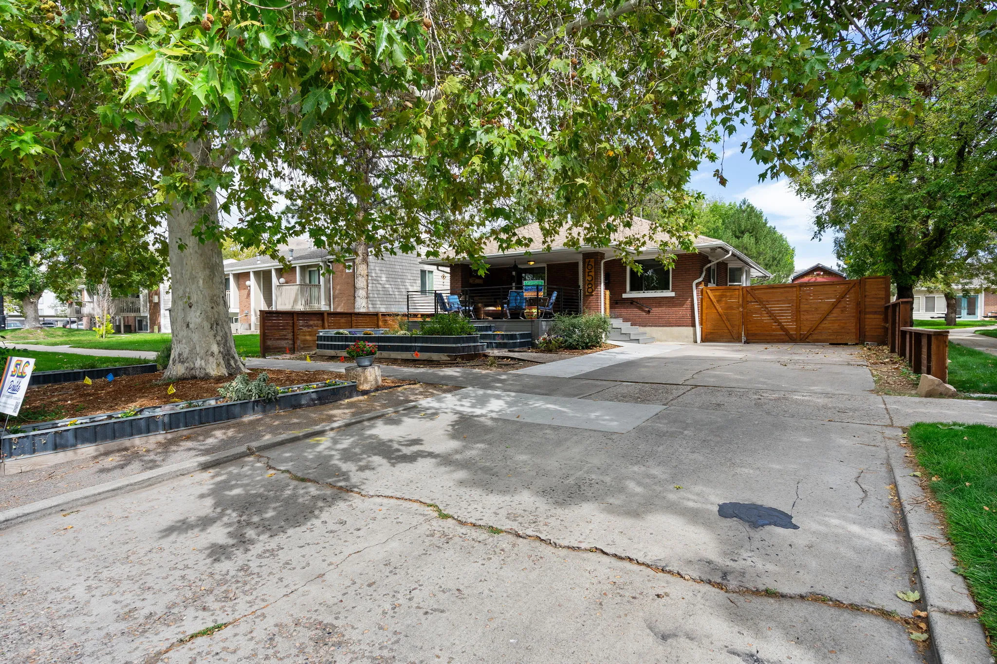 Brick exterior with a covered porch, mature trees, and a concrete driveway