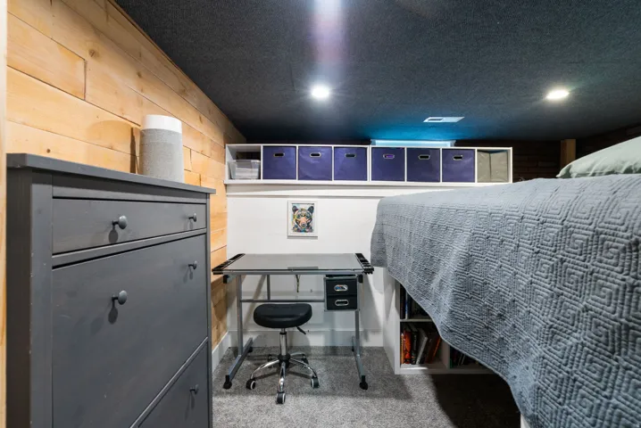 Wood-paneled wall accent, recessed lighting, built-in shelving, carpeted flooring, and a built-in platform bed frame