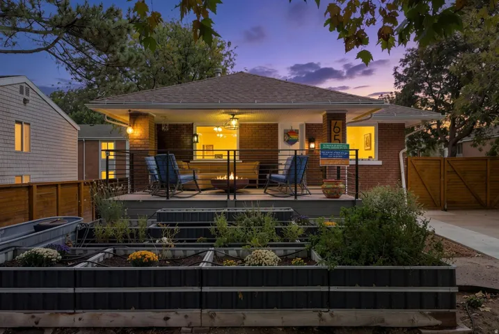 Brick exterior, covered porch, metal railing, multi-tiered raised garden beds, wood fencing
