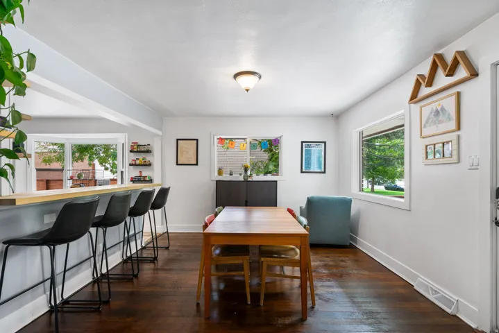 Hardwood flooring throughout, recessed lighting fixture, multiple windows providing natural illumination, and a built-in breakfast bar with a wood-finish countertop