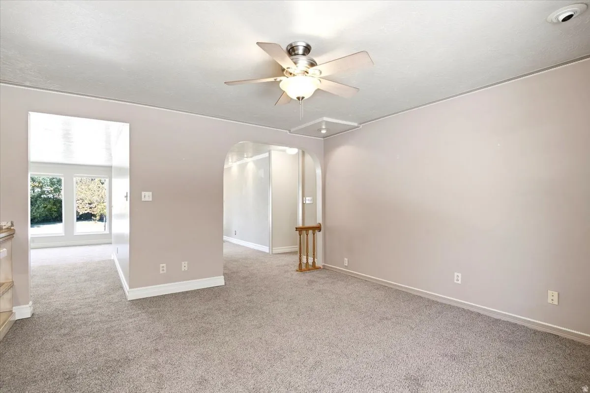 Recessed lighting, arched doorway, ceiling fan, white trim, and carpet flooring