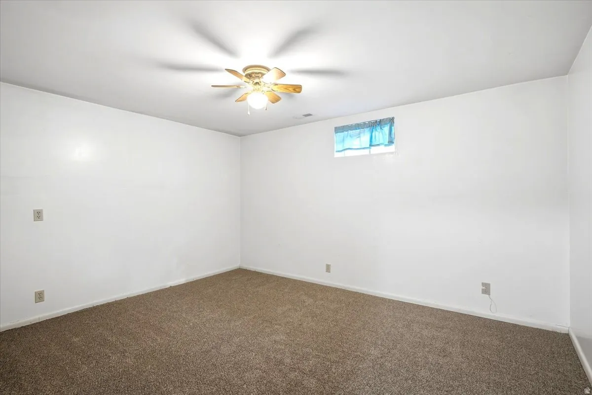Wall-to-wall carpeting and a ceiling fan with integrated lighting