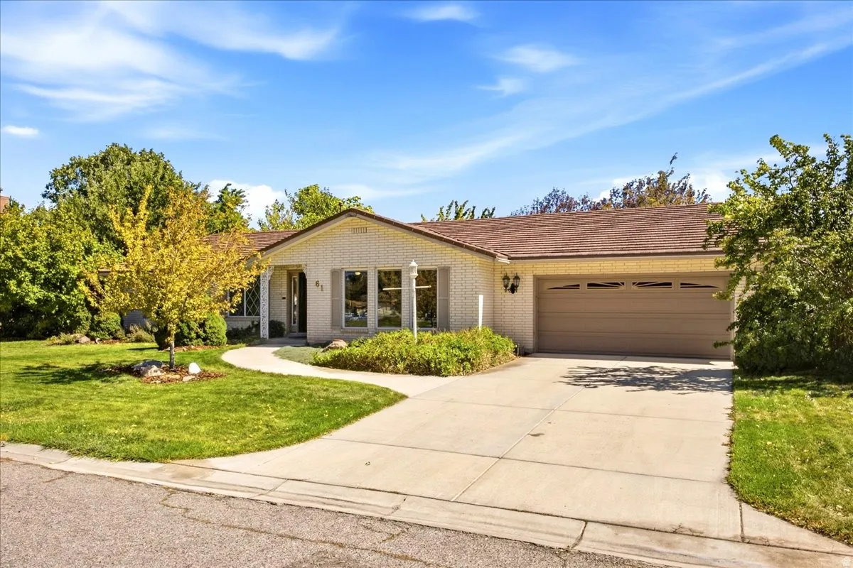 Single-story residence featuring a welcoming front elevation with a covered entry portico, multi-pane glass doors, and large picture windows