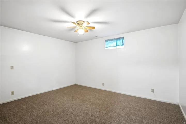 Wall-to-wall carpeting and a ceiling fan with integrated lighting