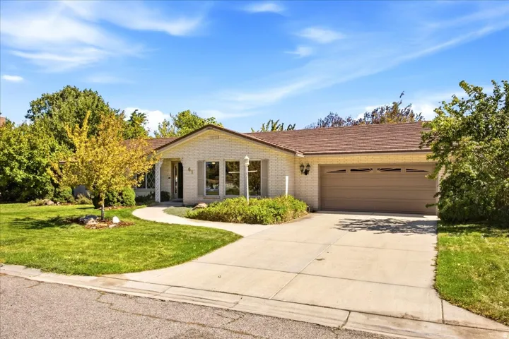 Single-story residence featuring a welcoming front elevation with a covered entry portico, multi-pane glass doors, and large picture windows
