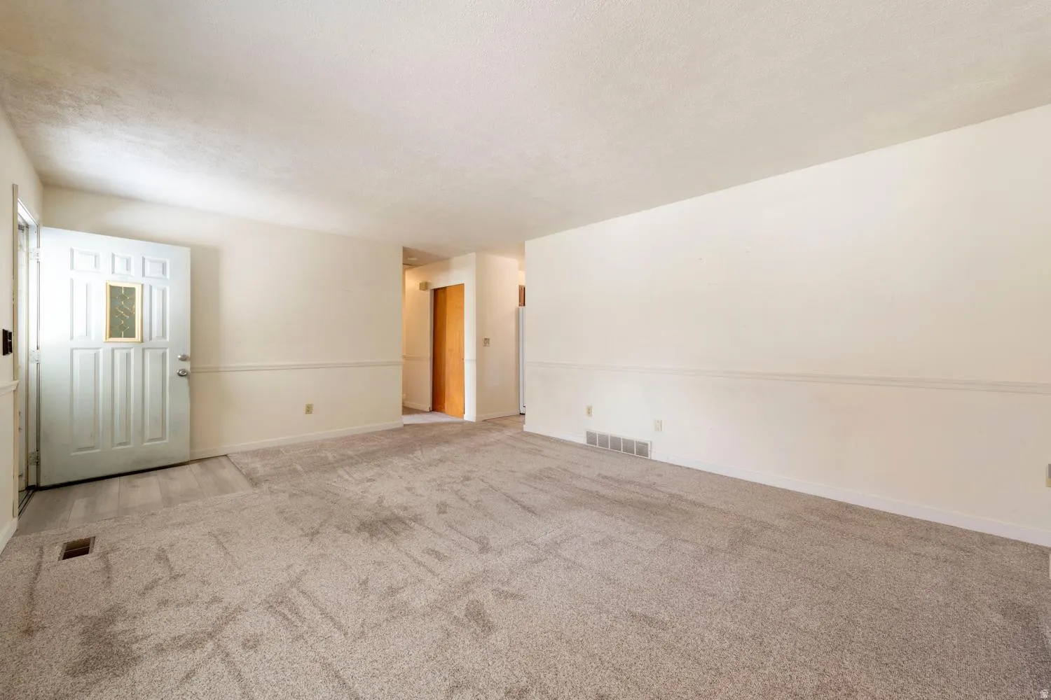 Carpeted living space with neutral wall tones and chair rail molding