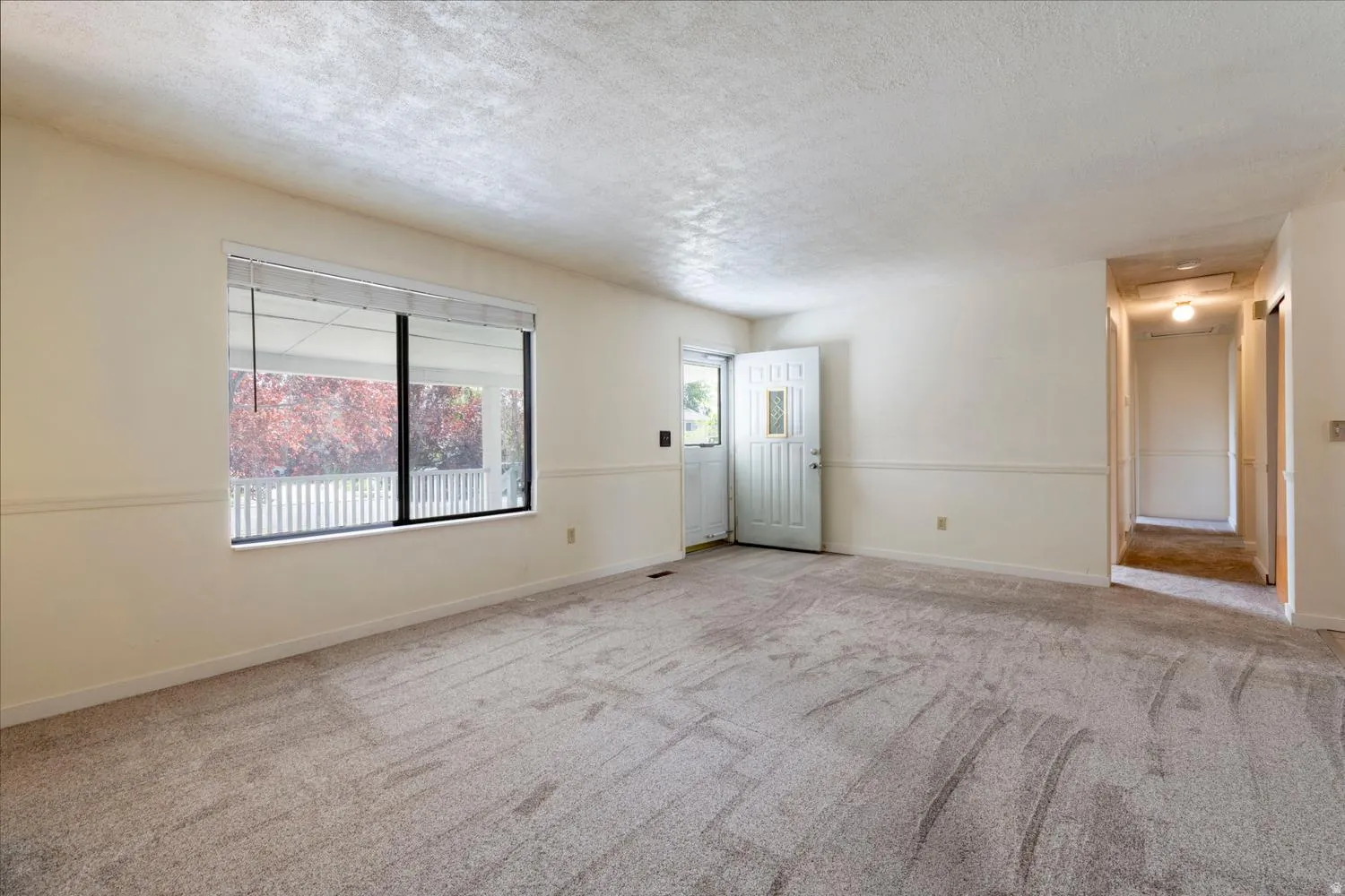 Spacious room with light neutral wall tones, textured ceiling, and gray patterned carpeting