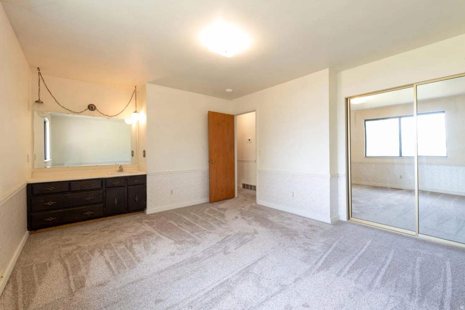Wall-to-wall carpeting, built-in vanity with mirror, built-in cabinetry, dual sliding mirrored closet doors, and recessed lighting