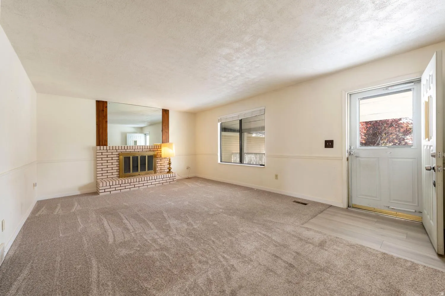 Brick fireplace with a brass firebox, wood beam accents, and an expansive mirror