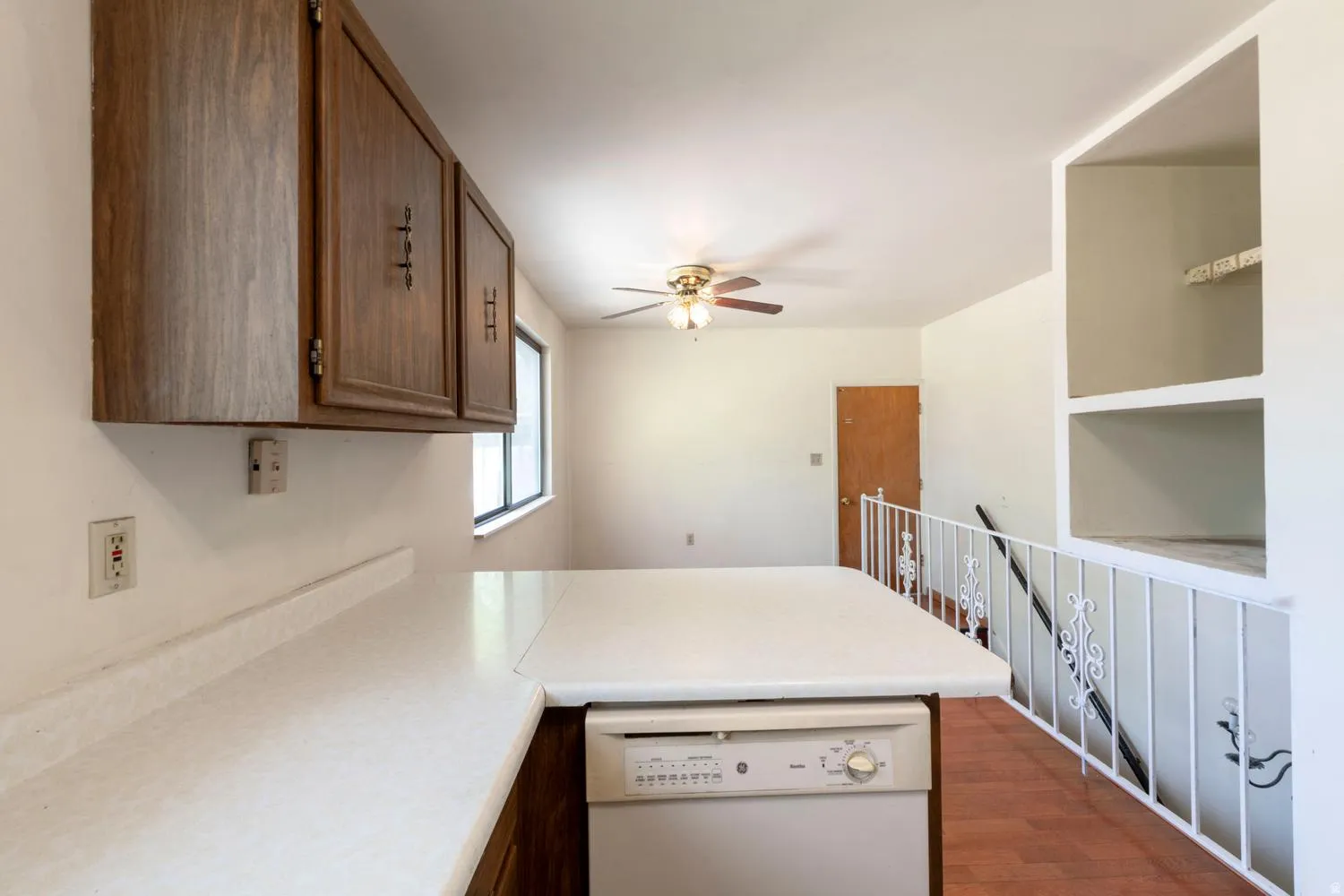 Kitchen featuring wood cabinetry, solid surface countertop, and an integrated dishwasher