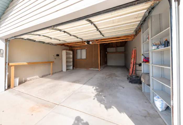 Concrete flooring garage with built-in workbench, and wall-mounted shelving.
