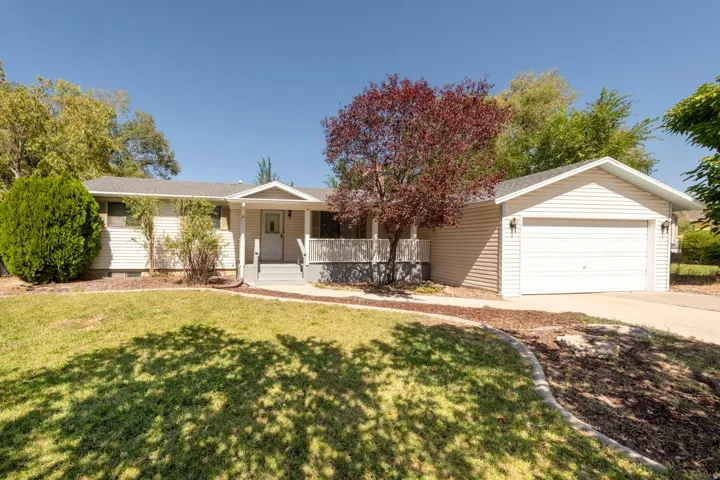 Siding exterior with a covered porch, attached two-car garage, and established landscaping