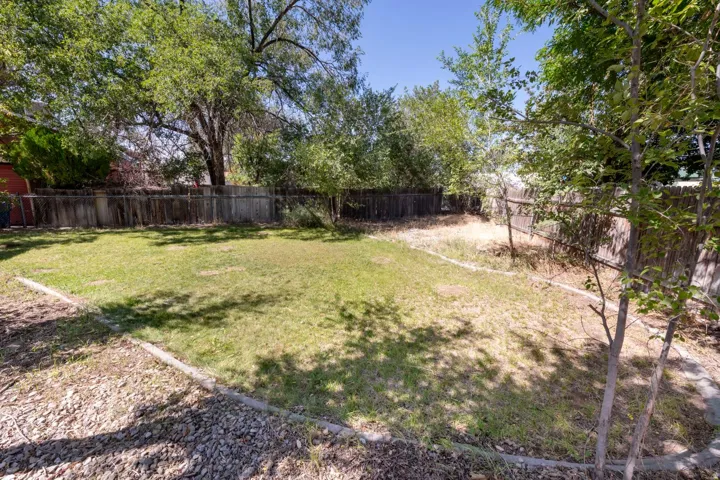 Spacious backyard featuring a fenced perimeter, mature trees, and a grassy area