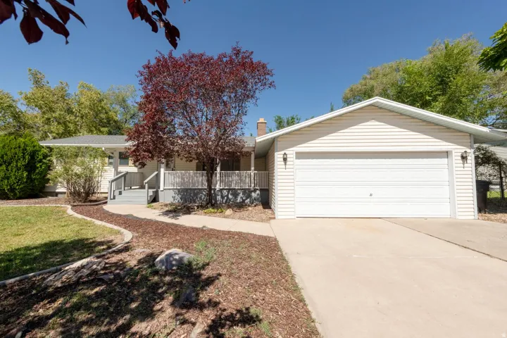 Siding exterior with an attached garage, concrete driveway, and front porch with railing