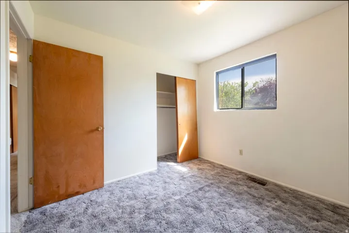 White walls, gray patterned carpeting, and a window