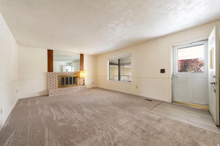 Brick fireplace with a brass firebox, wood beam accents, and an expansive mirror