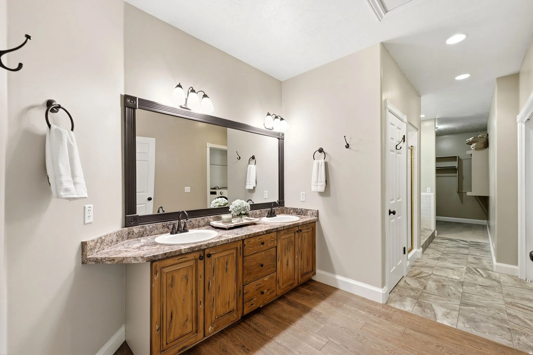 Dual vanity with wood-finish cabinetry, a framed mirror, and integrated lighting fixtures