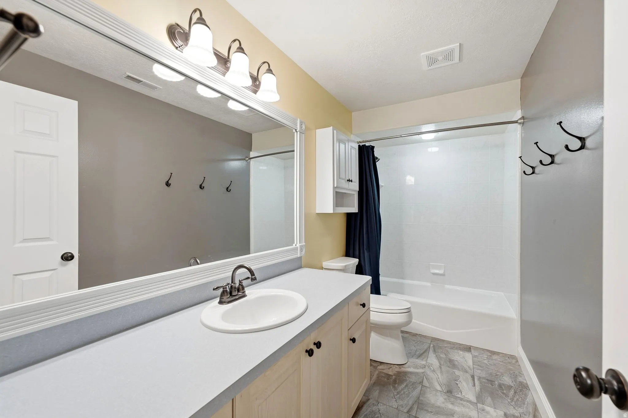 Vanity with integrated sink, bronze-finish faucet, and light wood-finish cabinetry