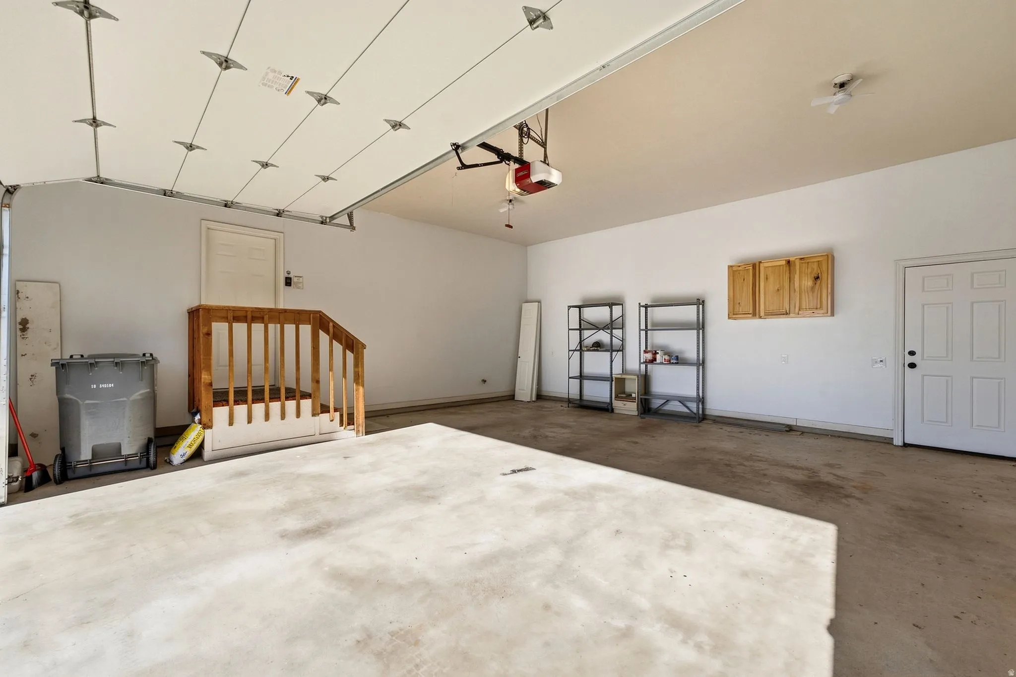 Attached garage with concrete flooring, wood-finish wall cabinetry, and interior access door