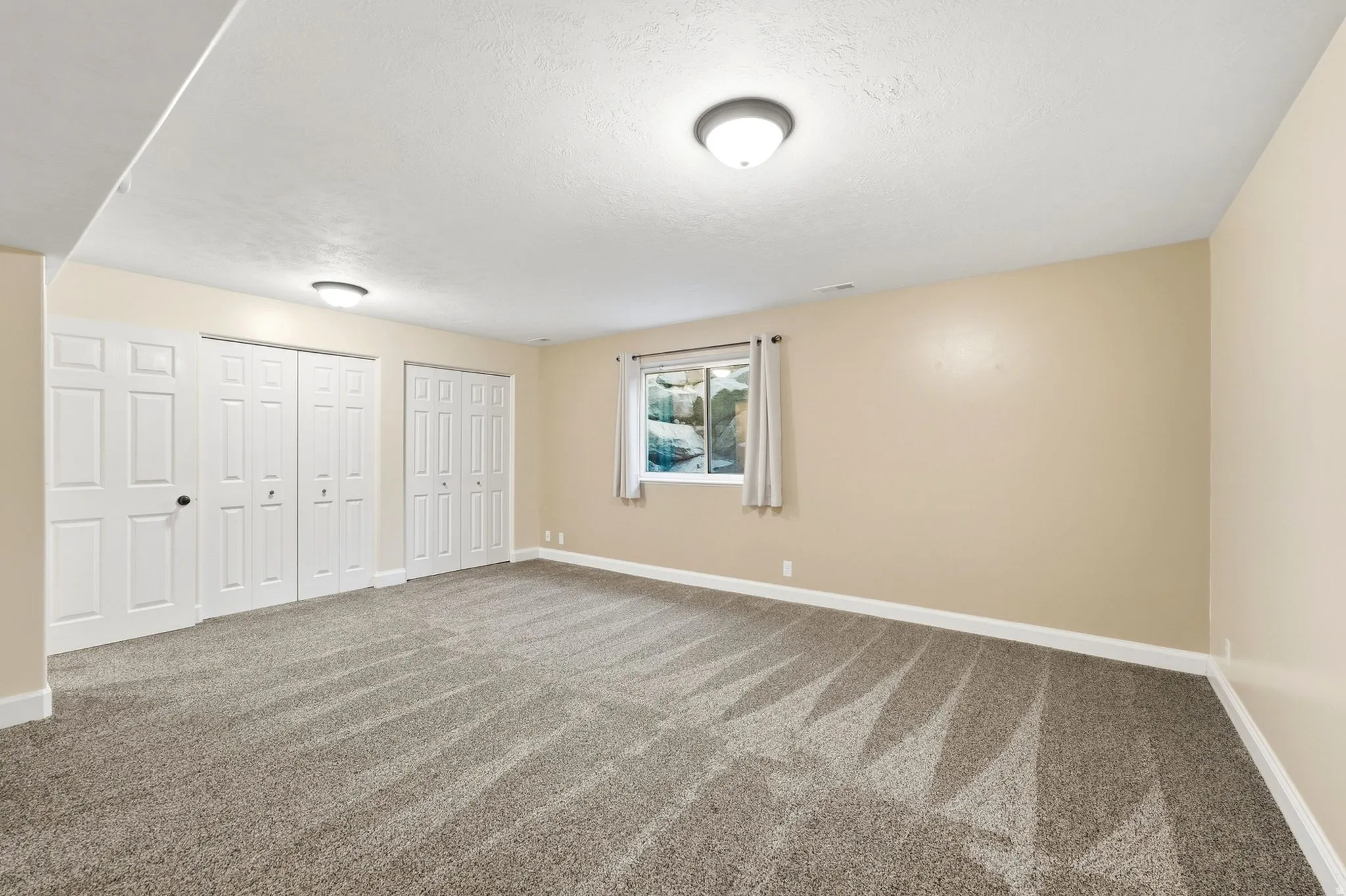 Cream-toned walls with contrasting white trim, neutral patterned carpet, white bi-fold closet doors, and recessed lighting