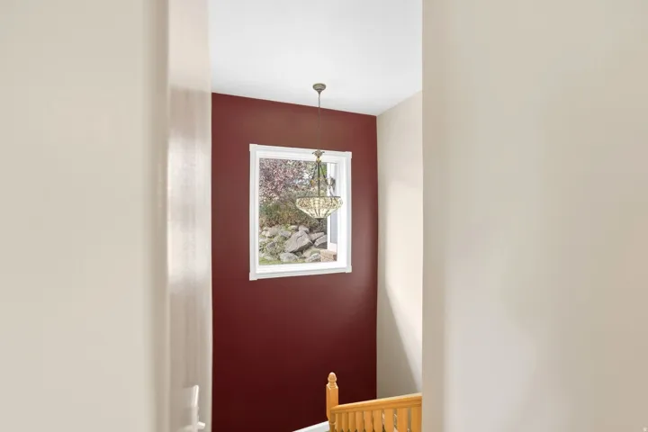 Stairwell with a decorative chandelier, white trim window, and wood handrail