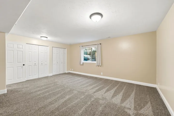 Cream-toned walls with contrasting white trim, neutral patterned carpet, white bi-fold closet doors, and recessed lighting