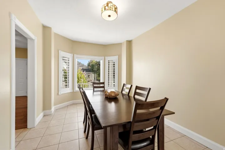 Bay window with white plantation shutters, tile flooring, and a semi-flush mount ceiling light fixture