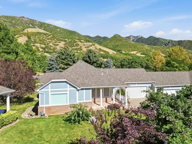Expansive mountain scenery, light blue siding exterior, attached multi-car garage, covered porch entrance, and mature landscaping