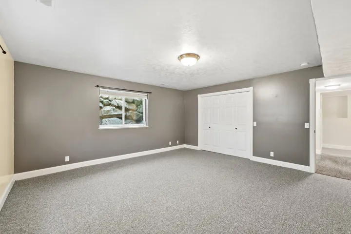 Carpeted interior space featuring a window, built-in closet with bi-fold doors, and a flush mount light fixture