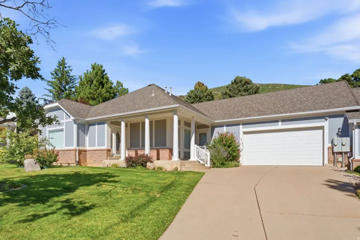 Entryway with substantial columns, light blue siding, brick accents, and a two-car garage