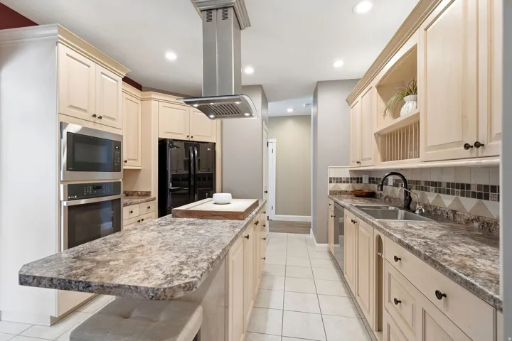Kitchen featuring light wood cabinetry, a large center island with an extended countertop, stainless steel appliances, and a tile backsplash