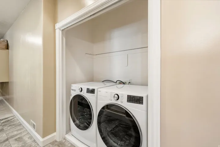 Built-in laundry closet with front-load appliances and overhead shelving