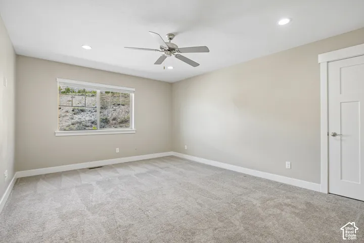 Neutral-toned walls, recessed lighting, ceiling fan, carpet flooring, and a window with white trim