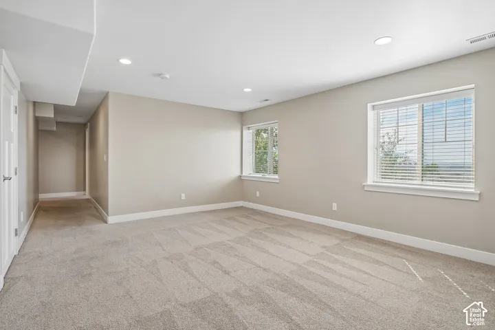 Recessed lighting, light-toned walls, and neutral-toned carpeting